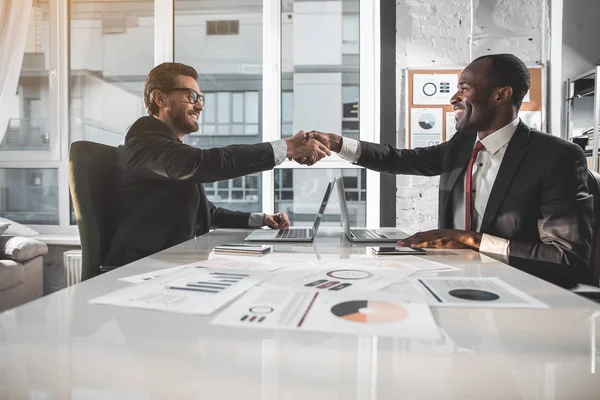 Positive businessmen are having firm handshake