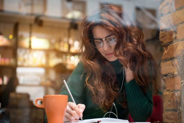 Cheerful girl making notes in writing-pad Stock Photo