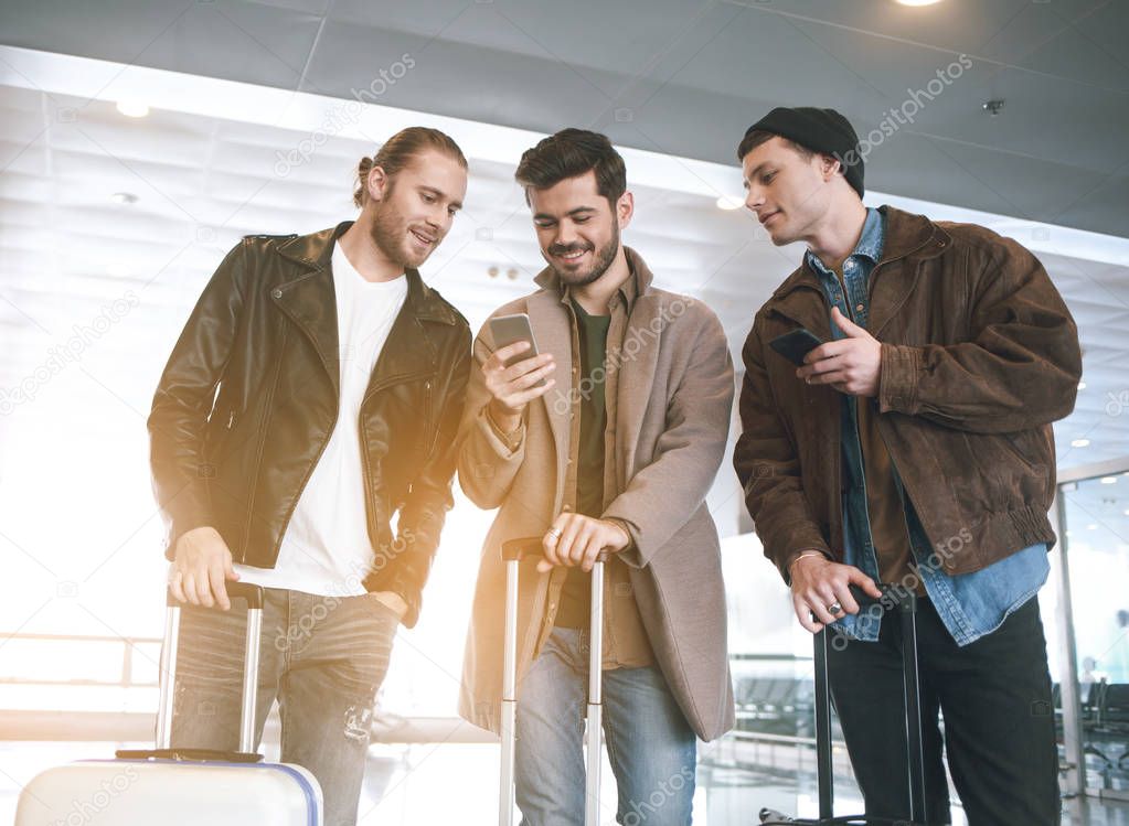 Happy males watching at phone at airport