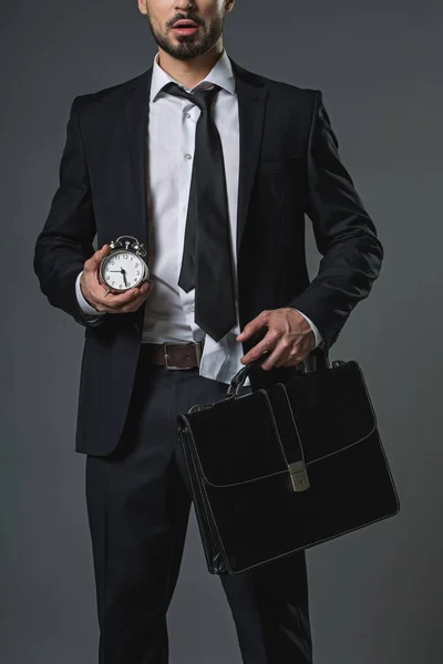 Hombre de negocios sorprendido de pie con reloj y maletín —  Fotos de Stock