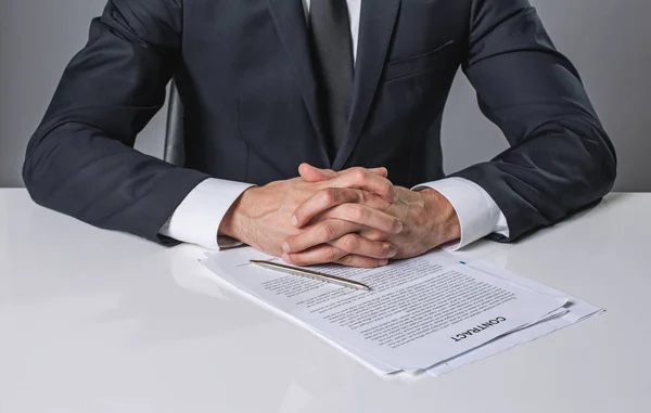 Joven hombre de negocios sentado en el escritorio cerca de acuerdo — Foto de Stock