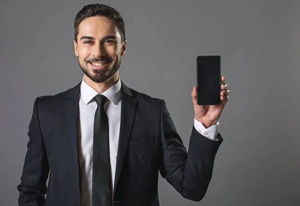 Mosolygó jóképű üzletember mutatja a modern okostelefon — Stock Fotó