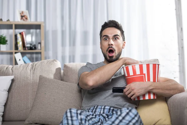 Amazed young male watching interesting movie — Stock Photo, Image