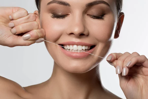 Joyful young woman touching tooth by dental floss — Stock Photo, Image