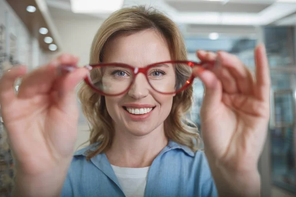 Alegre cliente femenino colgando gafas — Foto de Stock