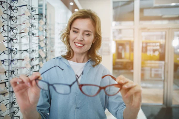 Alegre dama mirando gafas graduadas — Foto de Stock