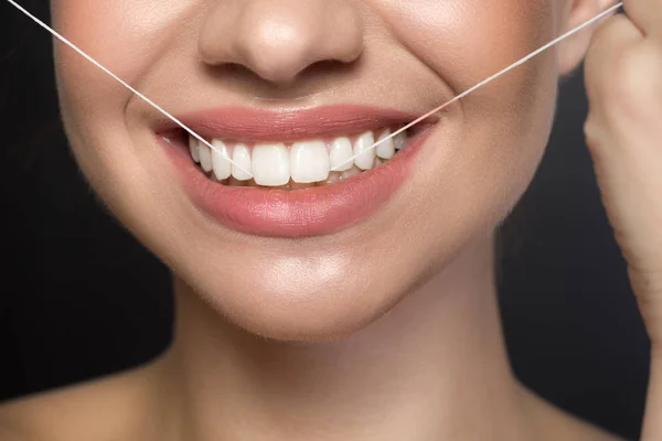 楽観的な若い女性は、歯間のフロスを使用しています。 — ストック写真