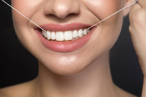 Optimistic young woman is using interdental floss