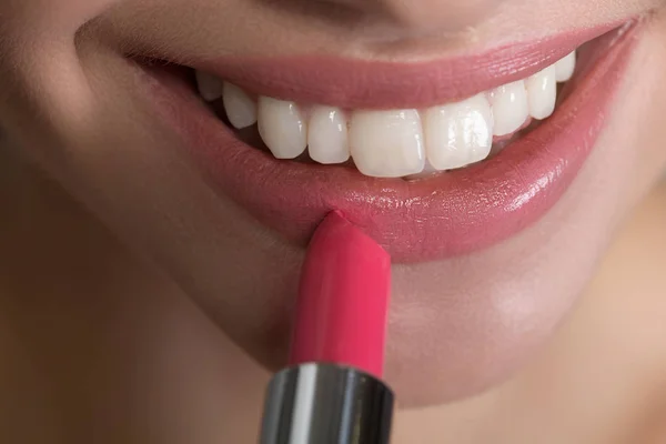 Sonrisa brillante de la mujer joven con el producto del maquillaje — Foto de Stock