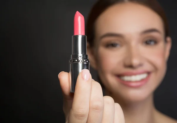 Fröhliche junge Frau zeigt Make-up-Produkt — Stockfoto