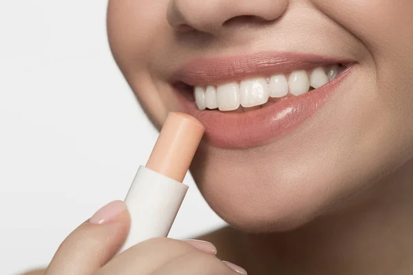 Fröhliche junge Frau trägt hygienischen Lippenstift auf — Stockfoto