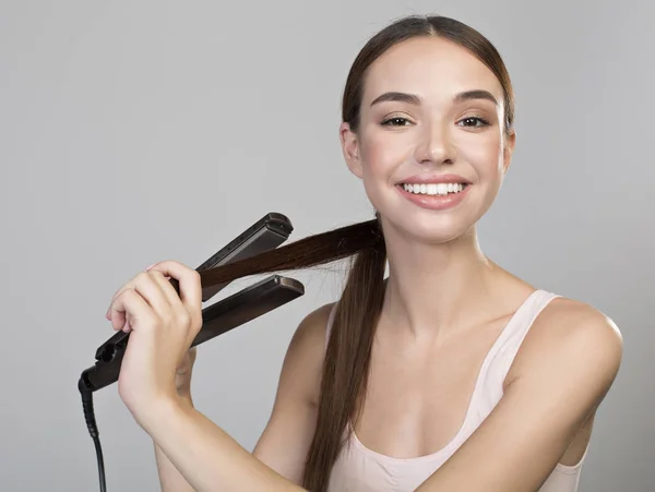 Menina alegre está usando alisador para cachos — Fotografia de Stock