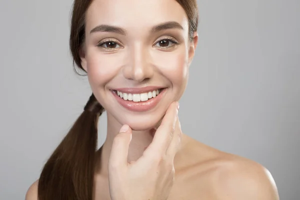 Positieve jonge vrouw raakt haar gezicht — Stockfoto