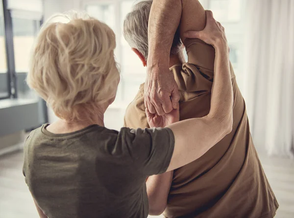 Gepensioneerde m/v-vrouw helpen om uit te voeren fysieke oefening — Stockfoto