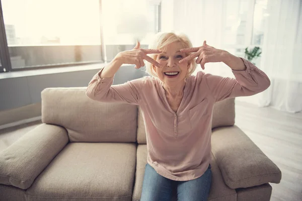 Оптимистичная бабушка сидит на диване в помещении — стоковое фото