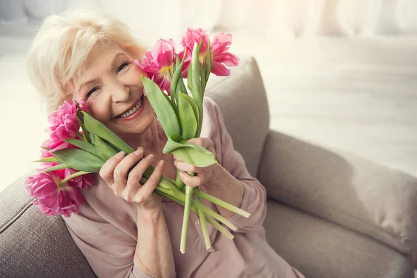 Senior zufriedene Frau genießt Frühlingsblumen — Stockfoto
