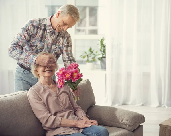 Oudere man zijn vrouw met bloemen te behagen — Stockfoto