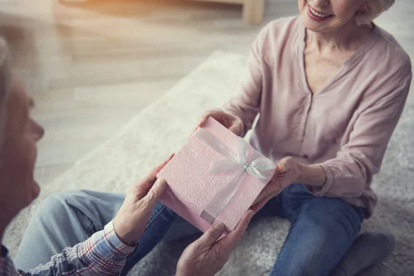 Anciano y mujer sosteniendo caja de regalo con alegría — Foto de Stock
