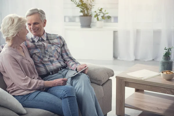 Feliz pareja de ancianos descansando con el dispositivo — Foto de Stock