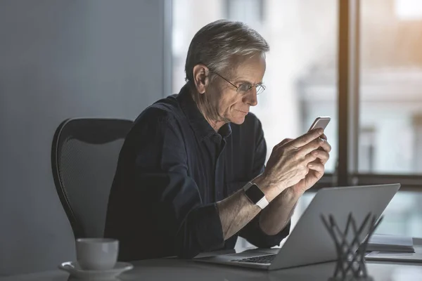 Serious old businessman typing in cellphone — Stock Photo, Image
