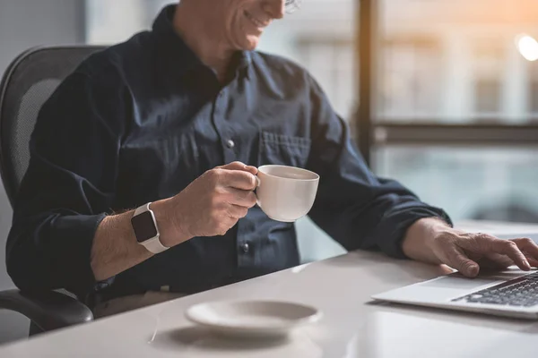 Cheerful old employer drinking mug of beverage — Stock Photo, Image