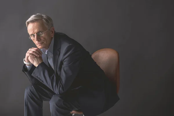 Pensive old businessman locating on chair — Stock Photo, Image