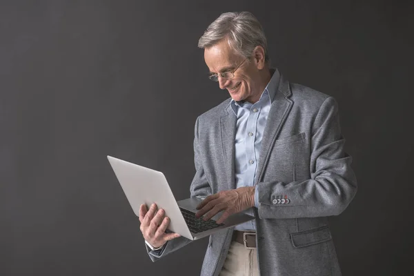 Zufriedener Rentner tippt in Notebook-Computer — Stockfoto