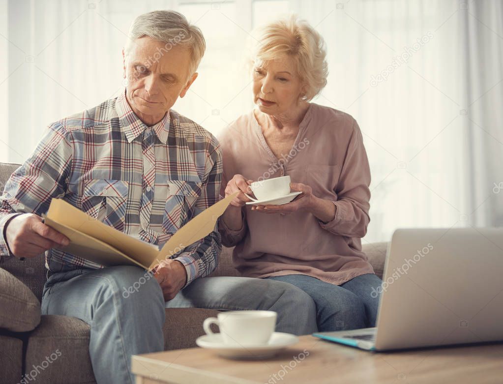 Married pensioners reading document together