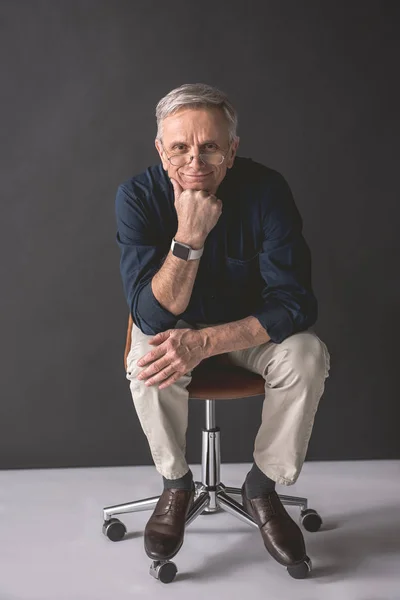 Cheerful mature male sitting on chair — Stock Photo, Image
