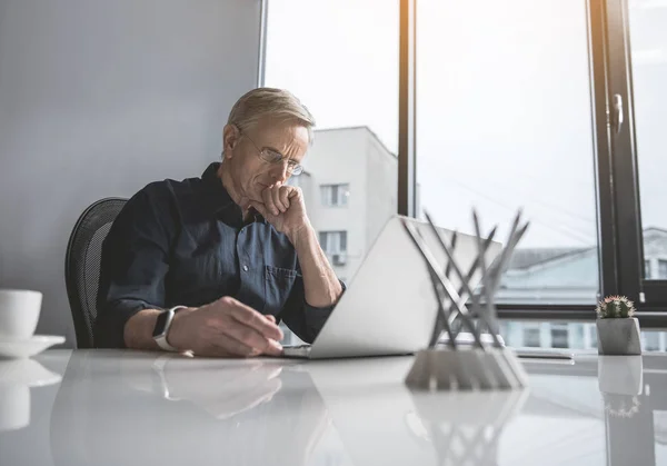 Fokuserade senior hane arbetar med gadget — Stockfoto