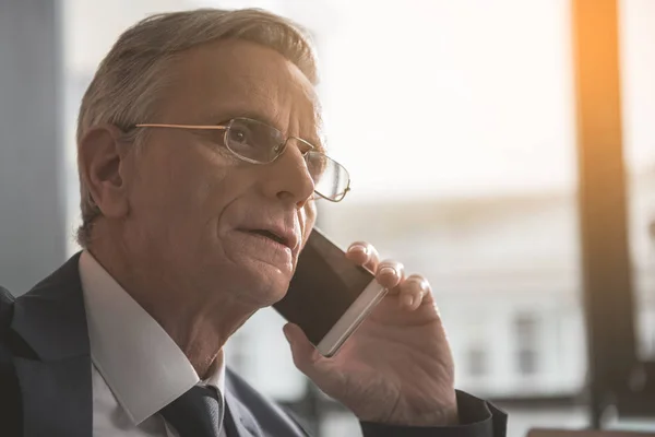 Focused senior businessman chatting by cellphone — Stock Photo, Image