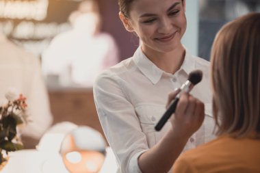 Neşeli kadın ziyaretçi için makyaj uygulamak