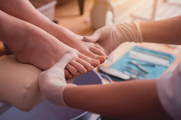 Girl hands in gloves holding feet — Stock Photo, Image