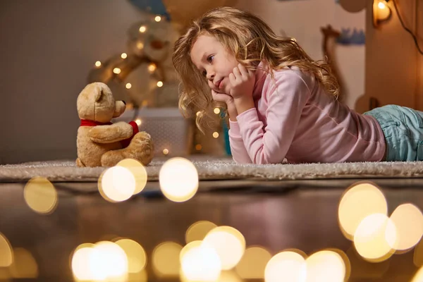 Chica pacífica en la alfombra con oso de juguete — Foto de Stock