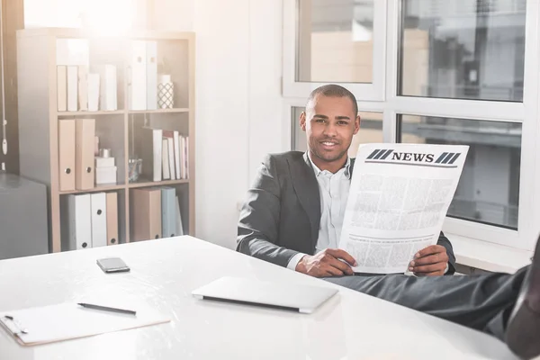 Handsome businessman relaxing with newspapers at cabinet