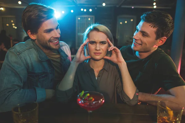 Desapontado feminino contando com homens alegres — Fotografia de Stock