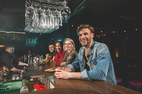 Amigos felices bebiendo bebidas en la mesa —  Fotos de Stock
