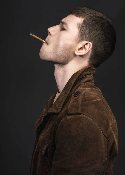 Jeune homme réfléchi allumant cigare — Photo