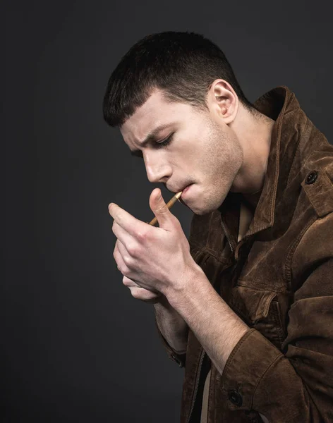 Jeune homme ordonné allumant cigare — Photo