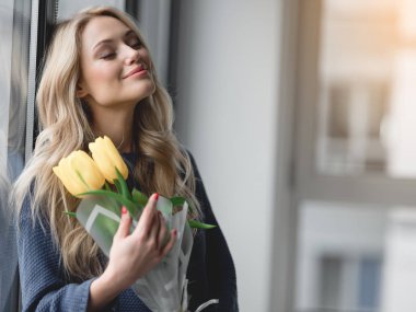 Sarı laleler tutan şirin genç kadın