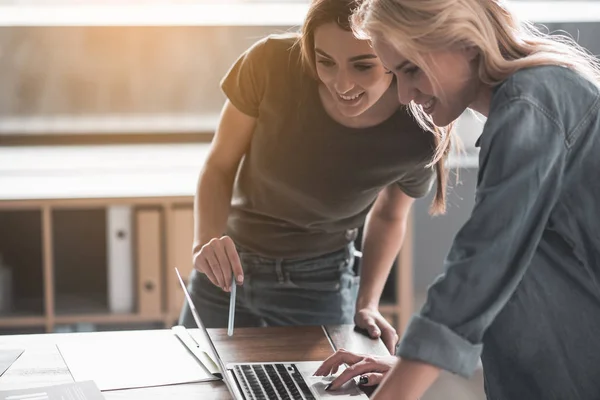 Blij vriendinnen die op laptop werkt — Stockfoto