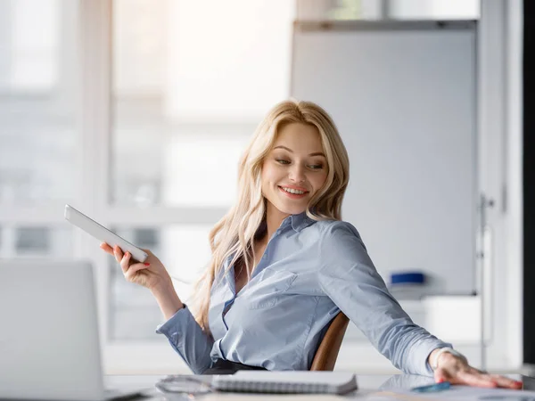 Jovem empresária feliz relaxando com gadget no escritório — Fotografia de Stock