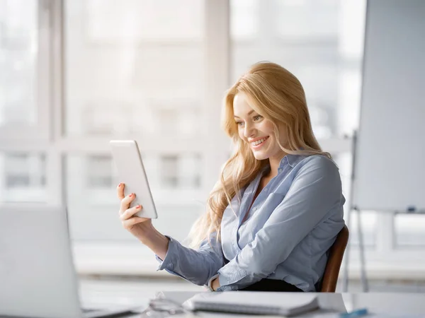 Glada kvinna använder moderna enhet på arbetsplatsen — Stockfoto