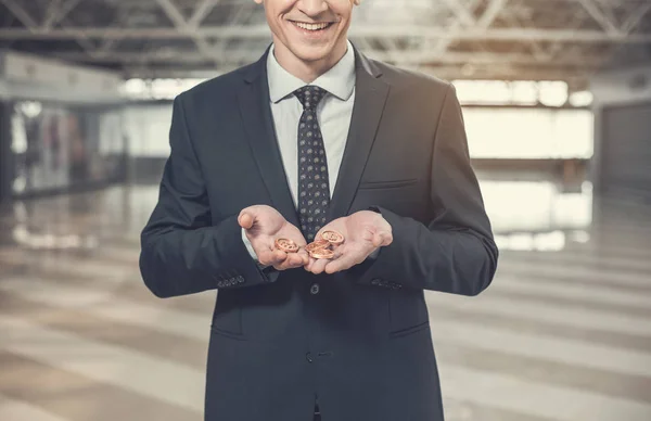 Hombre de negocios alegre sosteniendo bitcoins en la mano —  Fotos de Stock