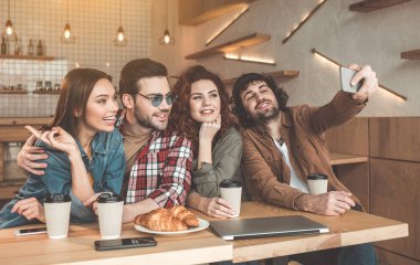 Neşeli öğrenciler kafede smartphone cep telefonu ile fotoğraf çekme