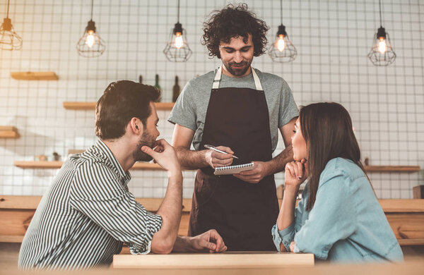 Friendly cafe worker talking with customers