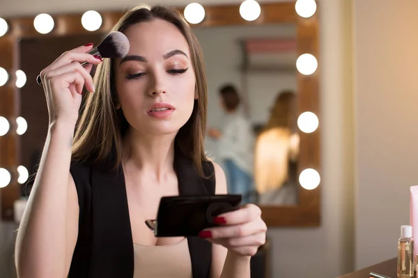 Charming girl is powdering her face — Stock Photo, Image