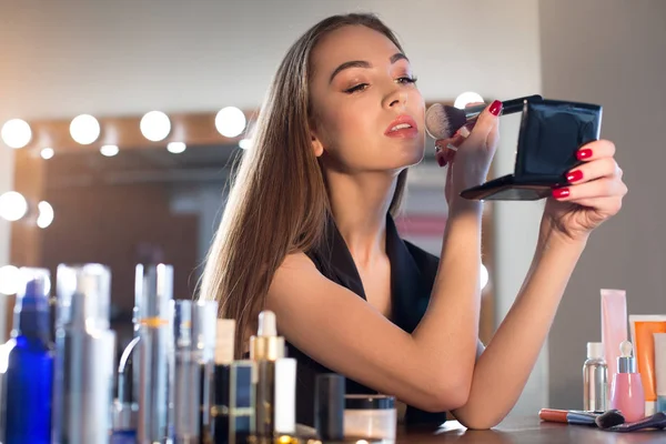 Attraktive junge Frau benutzt Pinsel, um ihr Gesicht zu pudern — Stockfoto