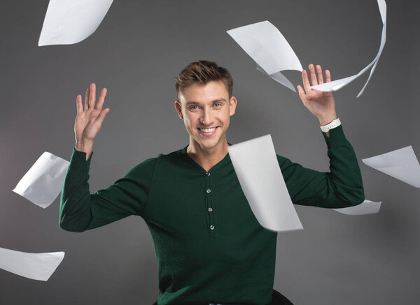Young man throwing up papers with happy face