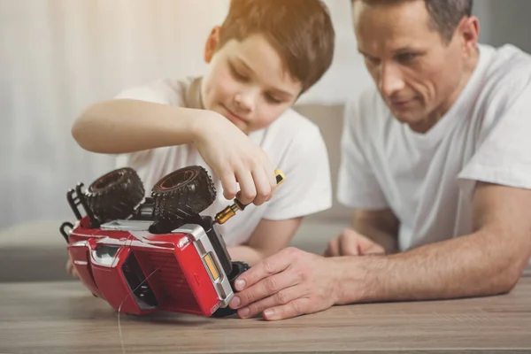 Padre está enseñando a hijo cómo reparar el transporte de juguetes —  Fotos de Stock